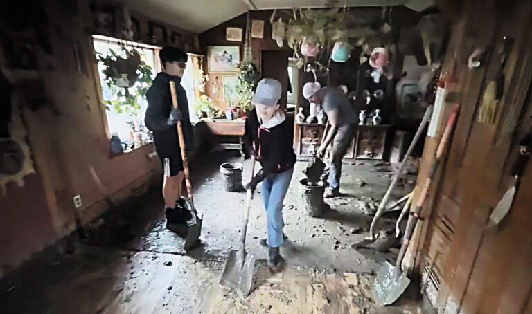 一場毀滅性的冬季風暴過後，志工們幫助萊特爾溪的一位居民清理家中淤泥。洛杉磯時報