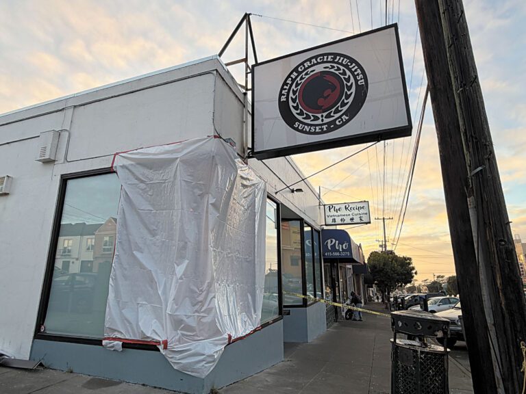 Noriega街與32大道街角建築外牆遭郵政貨車撞擊後，以塑膠帆布臨時覆蓋受損位置。記者蘇婕雅攝