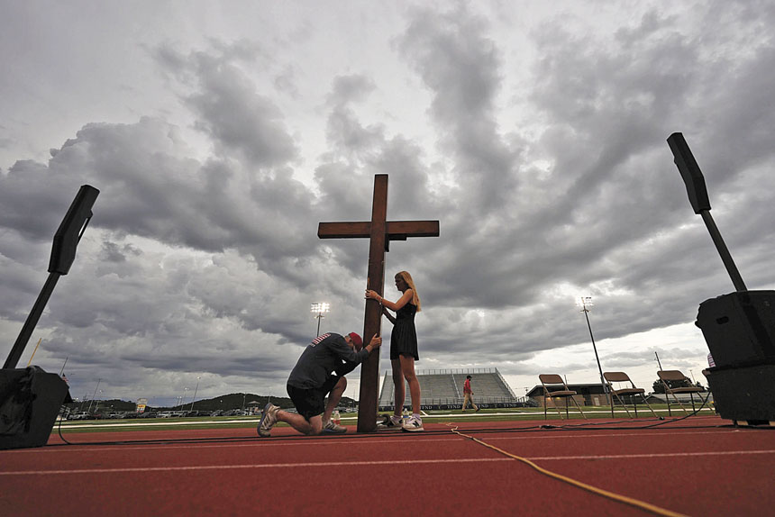 2025年7月,在德州克爾維爾的蒂維·安特勒體育場,來自密西根州的比茲利(左)與一名信眾一起手持一個大十字架,參加為洪水災民舉行的守夜活動。美聯社