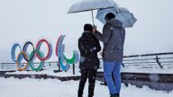 人們撐著傘冒雪站在科爾蒂納丹佩佐的奧運五環標誌旁。路透社