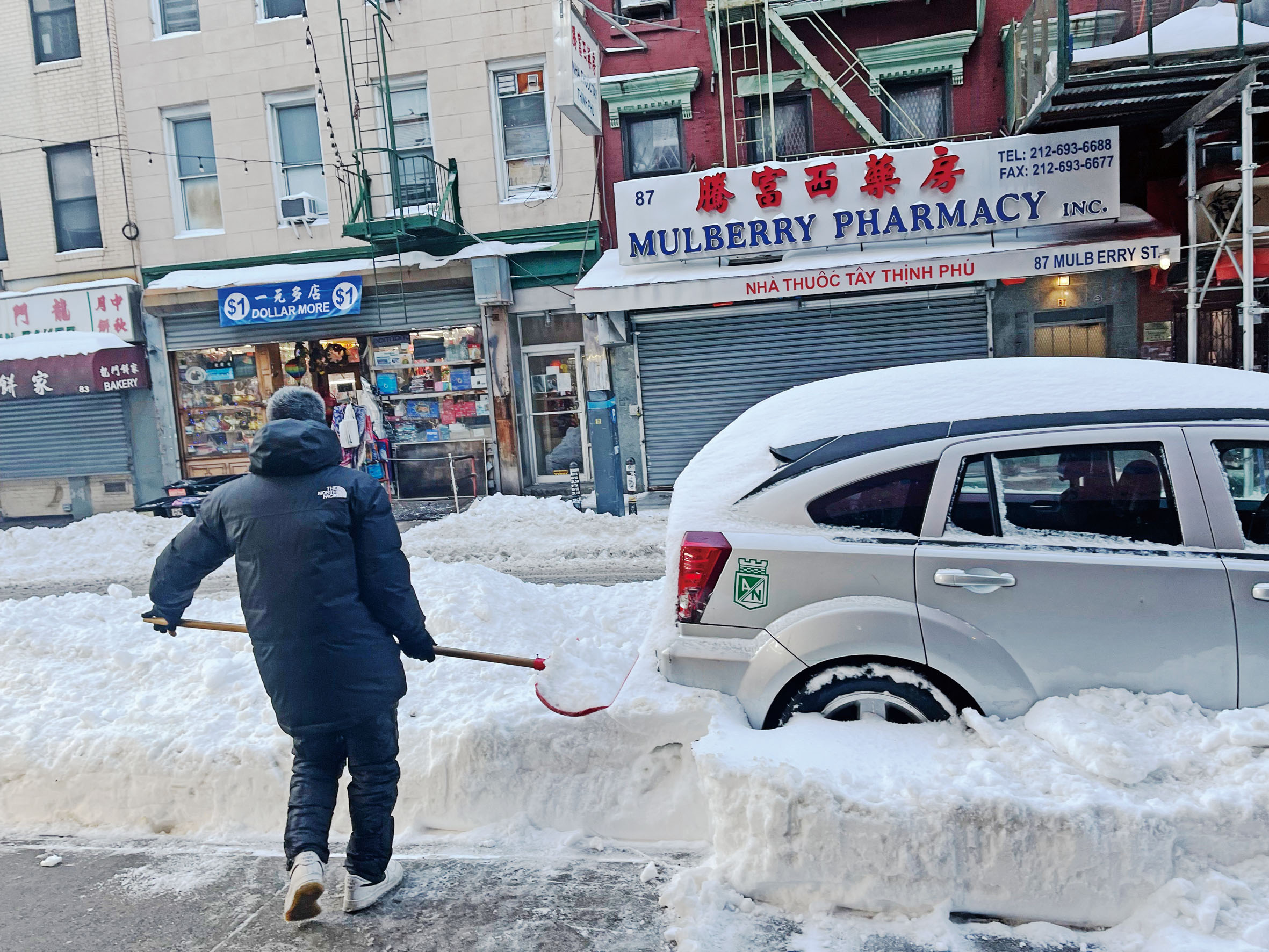 華人把車從積雪裡挖出來。