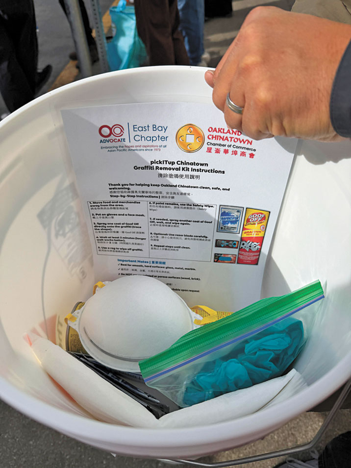 屋崙華埠商會與OCA東灣分會向商戶派發塗鴉清理工具桶，內含多款清潔劑、手套、口罩及中英對照使用說明。記者蘇婕雅攝