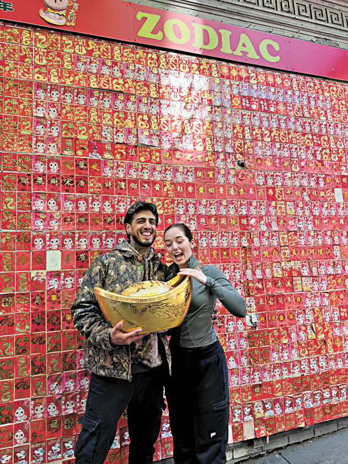 遊客在華埠生肖牆前拍照留念,手持象徵財富與祝福的金元寶,感受新年氣氛與華埠活力。記者蘇婕雅攝