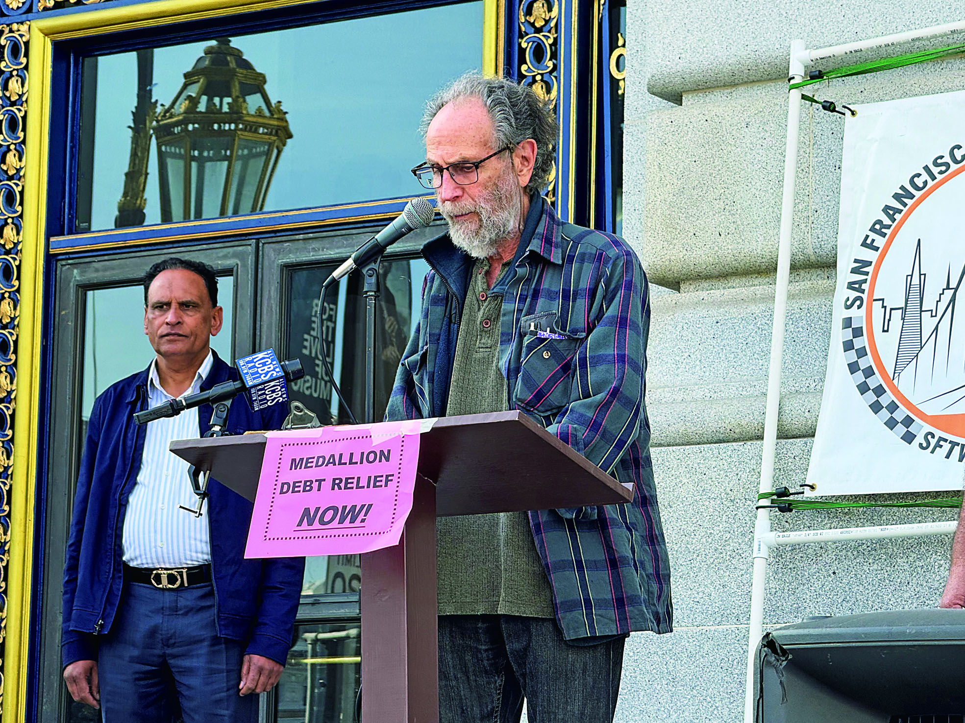 三藩市計程車工人聯盟理事會成員Mark Gruberg在市政廳前記者會上發言，批評計程車牌照制度失靈，導致司機背負沉重債務。記者陳程威攝