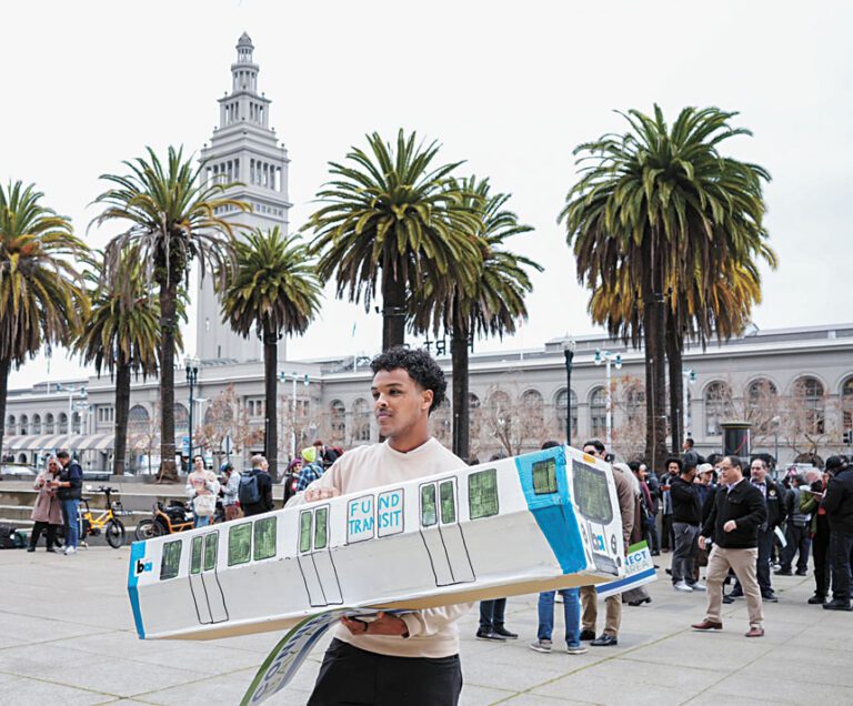 支持資助公共交通系統的集會上，參與者高舉紙板捷運。灣區城市新聞社