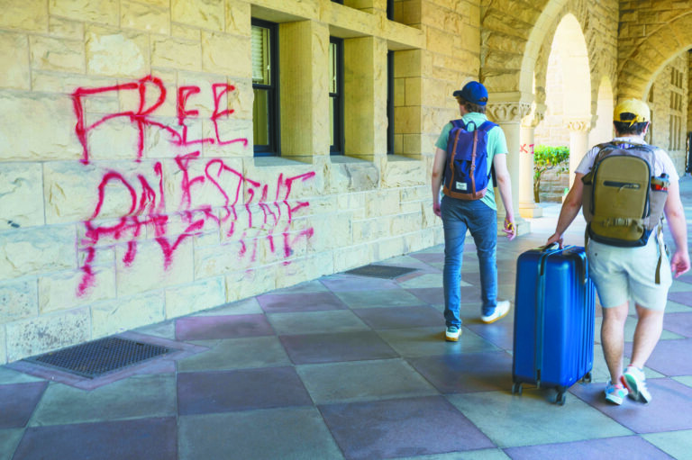 圖為兩名史丹福大學學生2024年6月5日走過靠近校長辦公室外牆的塗鴉。美聯社資料圖片