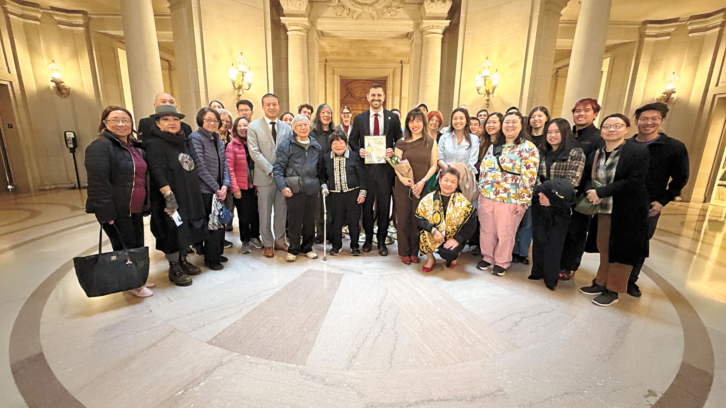 三藩市市參事李爾德(前排中)向市立大學資深粵語教師余天璇(前排左3)頒發表揚狀,感謝其近半世紀致力推廣粵語教育。市參事辦公室提供