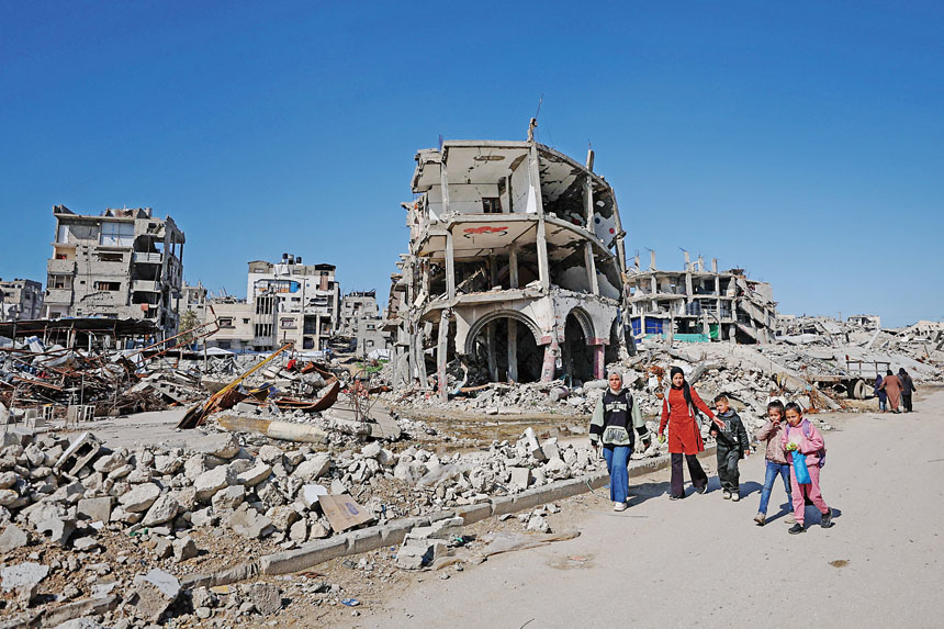 加沙大量建築物因戰火遭到破壞。圖為加沙居民走過被摧毀的居民樓廢墟。路透社