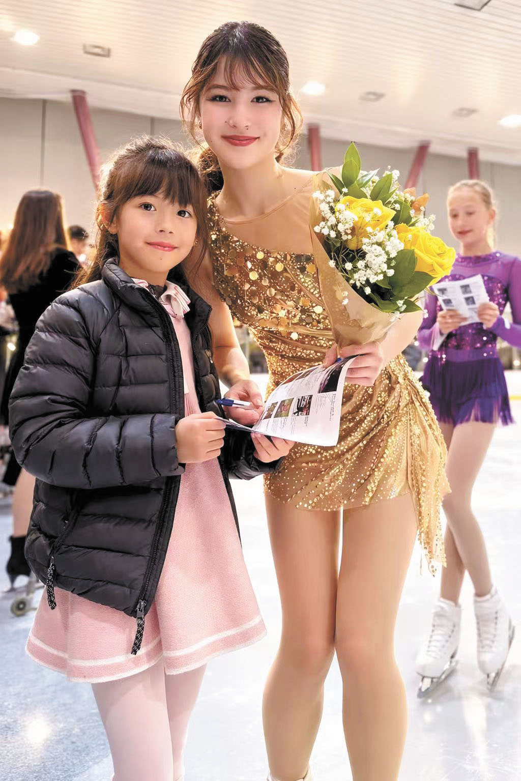劉美賢（左）2025年在三藩市冰場活動中與小師妹Diana合照，親切為她簽名留念。受訪者提供