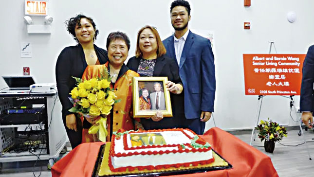 2019年華人諮詢服務處感激黃任朝、黃羅瑞雄伉儷對社區的貢獻，將樂宜居老人大廈易名為「黃任朝、黃羅瑞雄樂宜居老人大廈」，當天黃羅瑞雄（前左1）手持先生的遺照與女兒（前右1）及兩外孫留影。本報檔案照/梁敏育攝