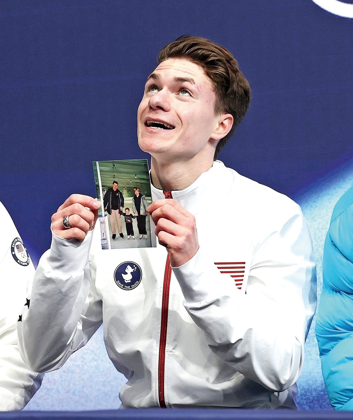 諾莫夫在冬奧會現場舉起一張他父母和他小時候的合影照片。