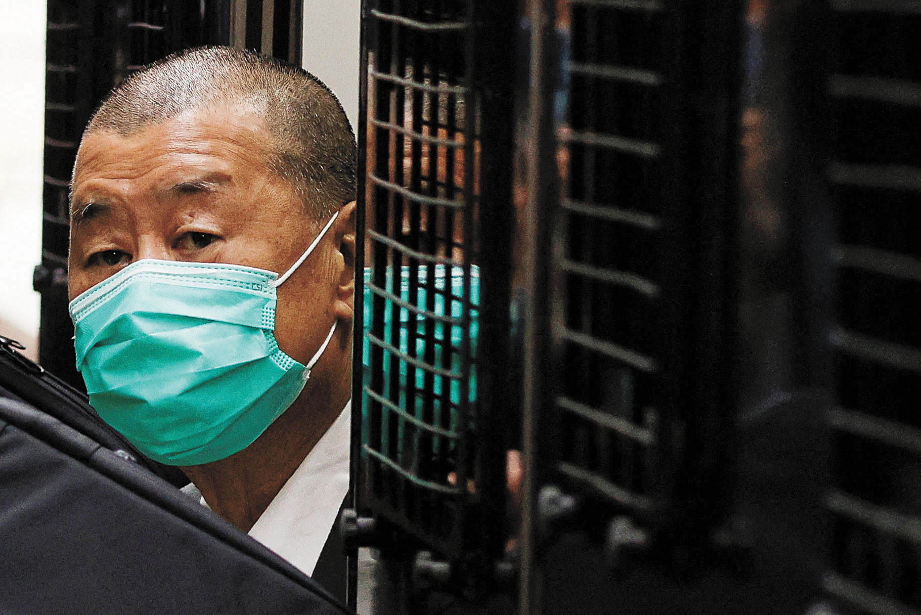 黎智英9日走出囚車時身著深色西裝,帶著口罩。路透社