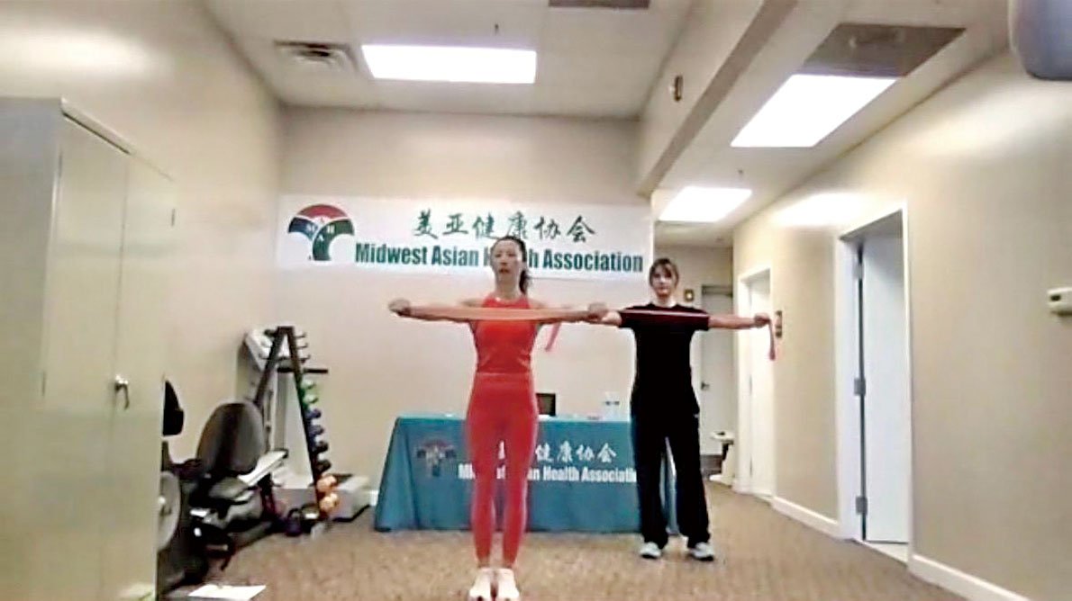 國家級體操運動員、健身操國家課題組成員于暉老師(前)指導學員們練習彈力帶操。	    梁敏育攝