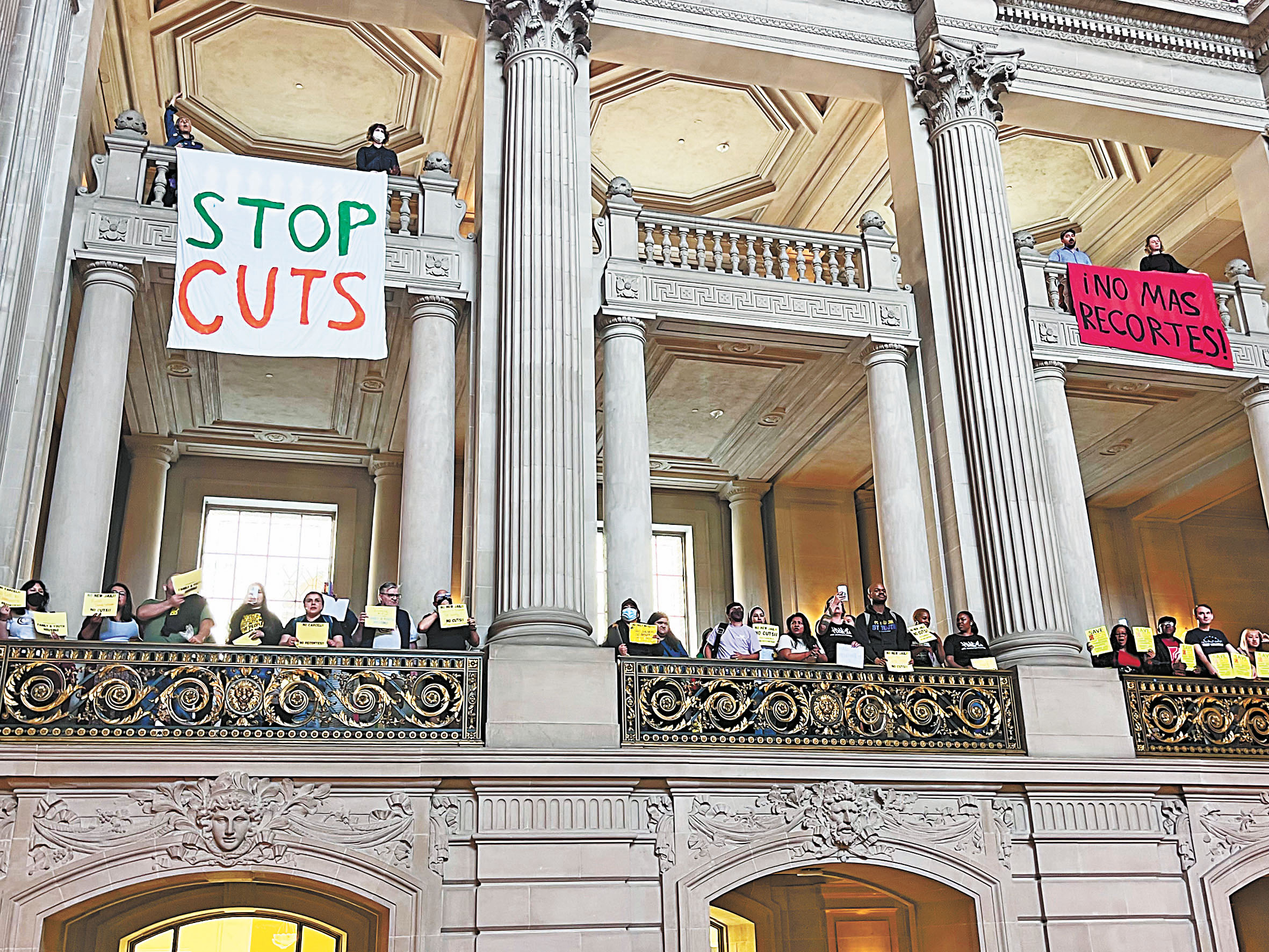 三藩市市長羅偉計劃削支裁員，圖為去年6月市府預算協商期間工會代表在市參事會上舉標語呼籲不要削減。本報資料圖片，記者陳程威攝