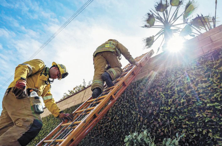 洛杉磯縣消防員在克萊蒙特210號高速公路旁清理火災現場。洛杉磯時報