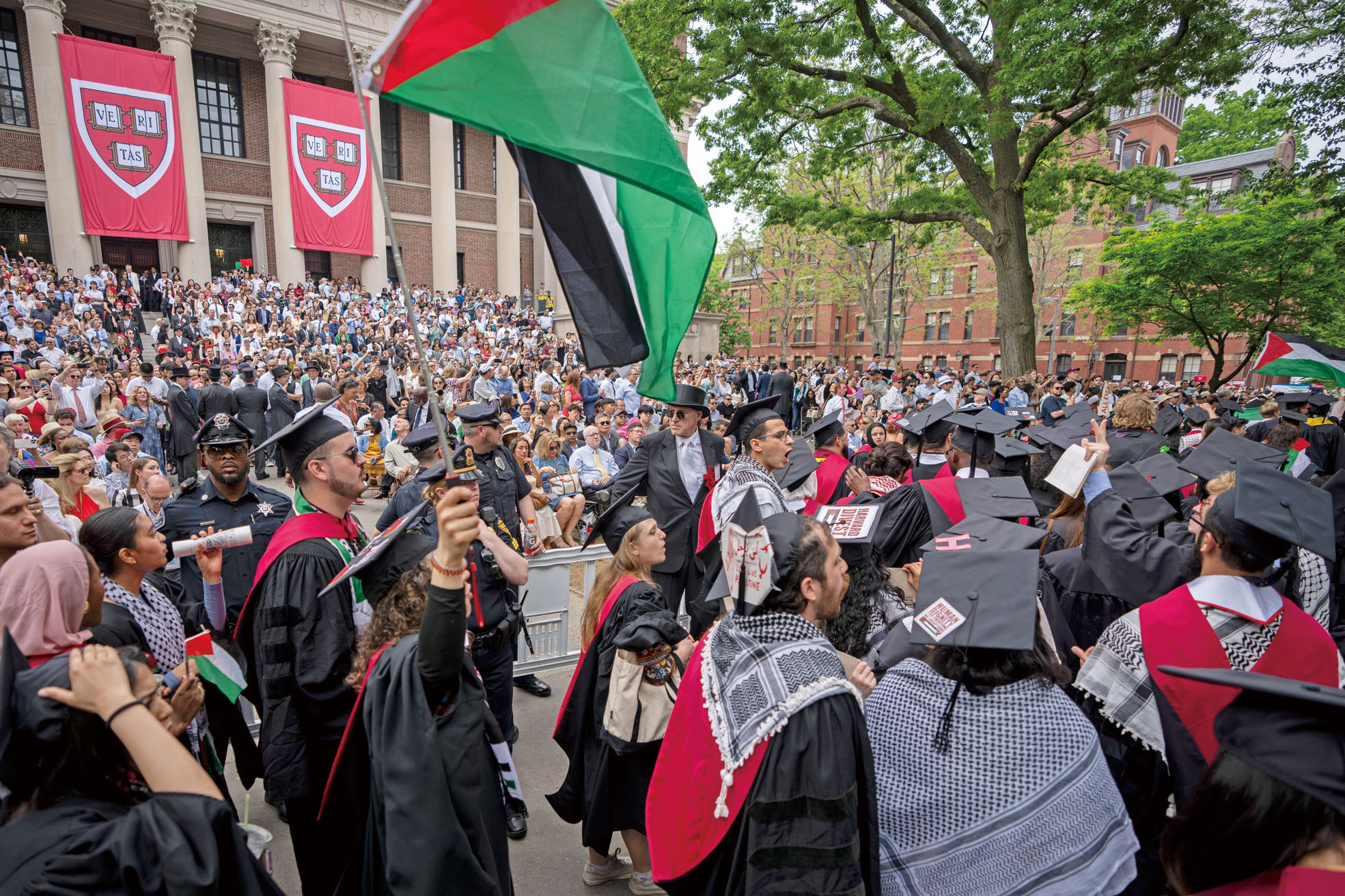 2024年5月23日，哈佛大學畢業典禮期間，多名學生揮舞巴勒斯坦旗幟並離場抗議，反對校方禁止13名因參與示威活動而受到紀律處分的學生畢業。美聯社資料圖片