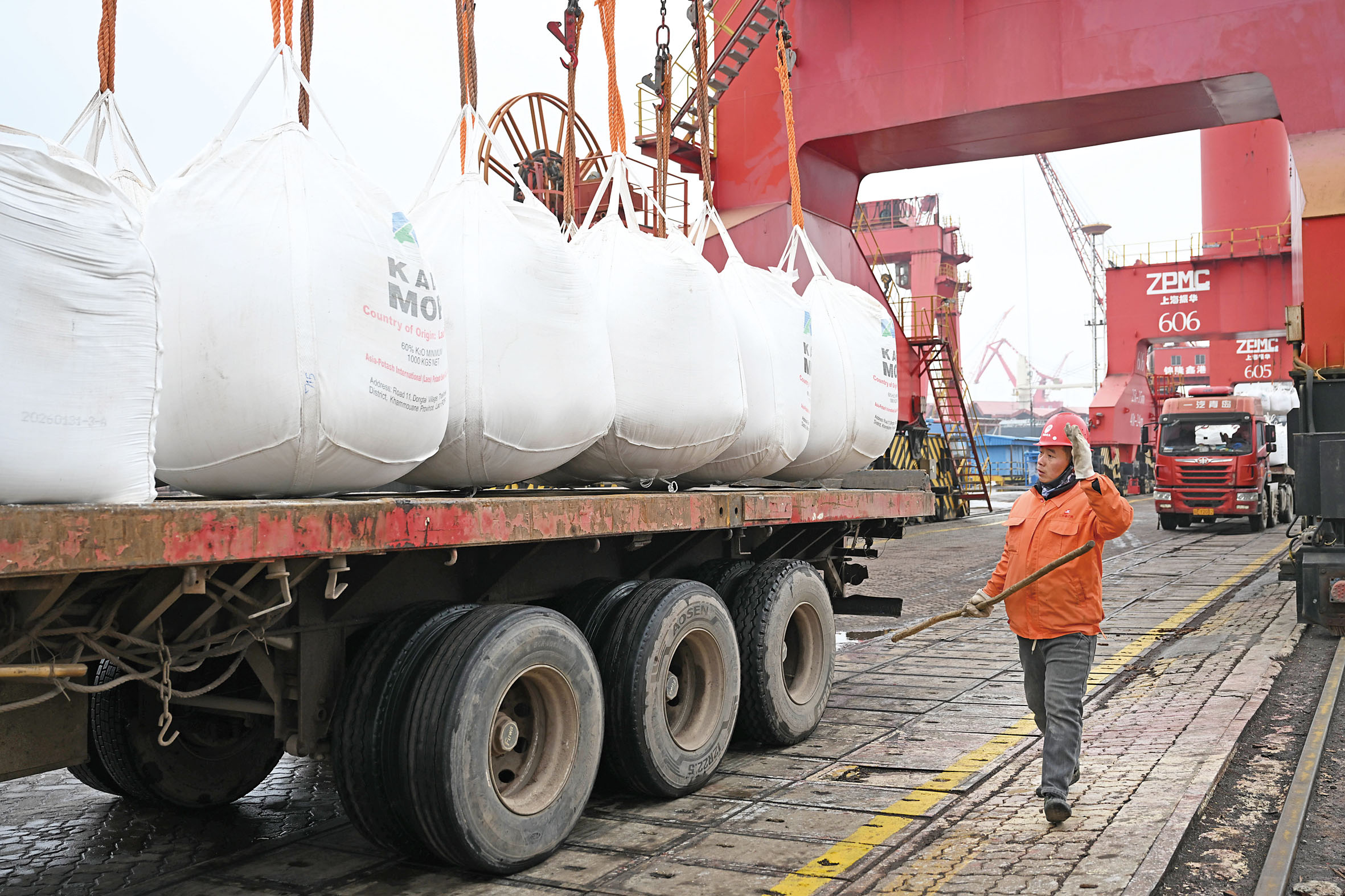 圖為在中國張家港錦隆重件碼頭，工人指揮卸運化肥。新華社