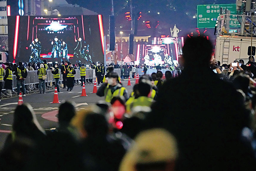 警方在轉播大屏幕前設置層層路障防止人潮聚集，沒座位的歌迷只能遠遠的看偶像表演。美聯社