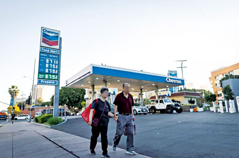 兩名行人走過華埠一間加油站，該站油價格接近每加侖九元。洛杉磯時報