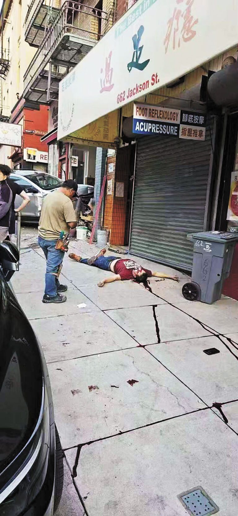 人行道上一名拉美裔壯漢倒地不起，鮮血沿著水泥地的縫隙往斜坡下流淌，畫面令人揪心。路人提供