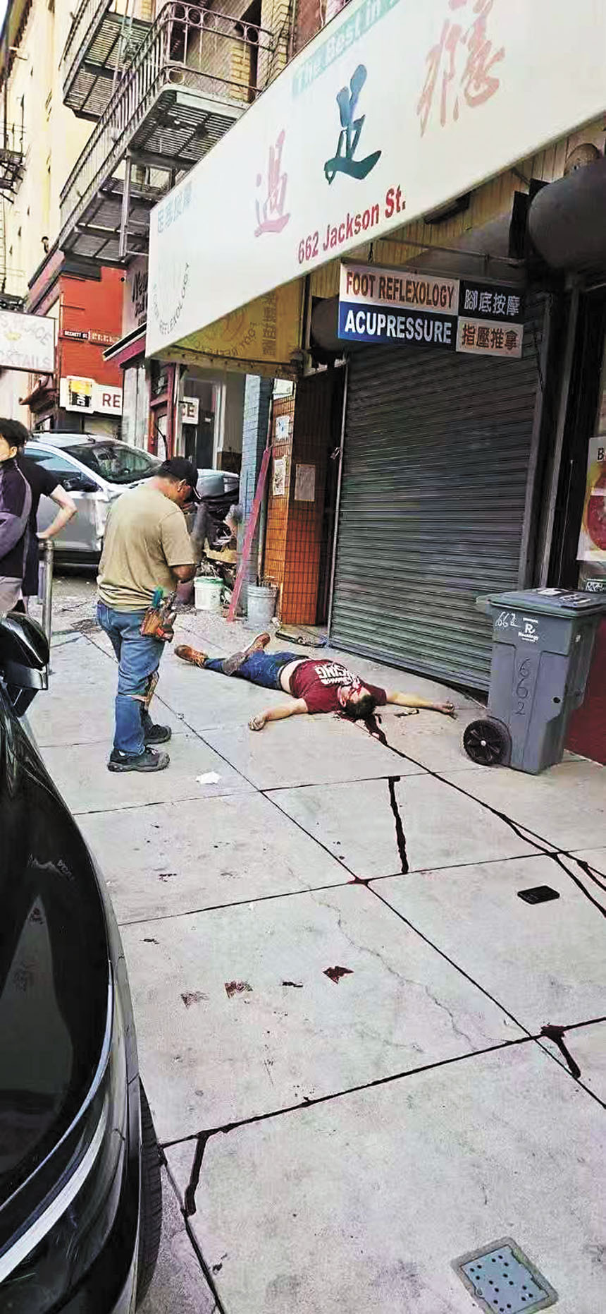 人行道上一名拉美裔壯漢倒地不起，鮮血沿著水泥地的縫隙往斜坡下流淌，畫面令人揪心。路人提供