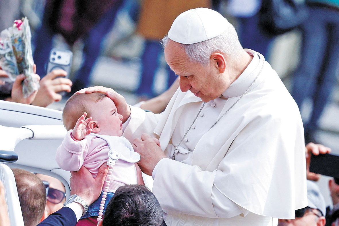 教宗在梵蒂岡聖枝主日彌撒結束後離開時，為一名嬰兒祝福。路透社