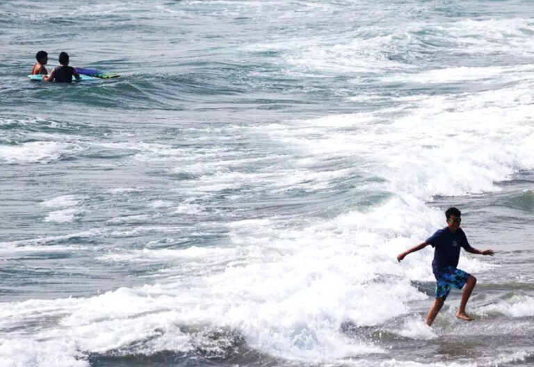 一名少年在杭廷頓灘的海浪中奔跑。洛杉磯時報