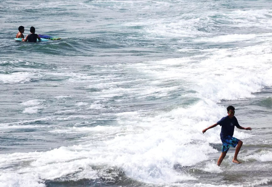 一名少年在杭廷頓灘的海浪中奔跑。洛杉磯時報