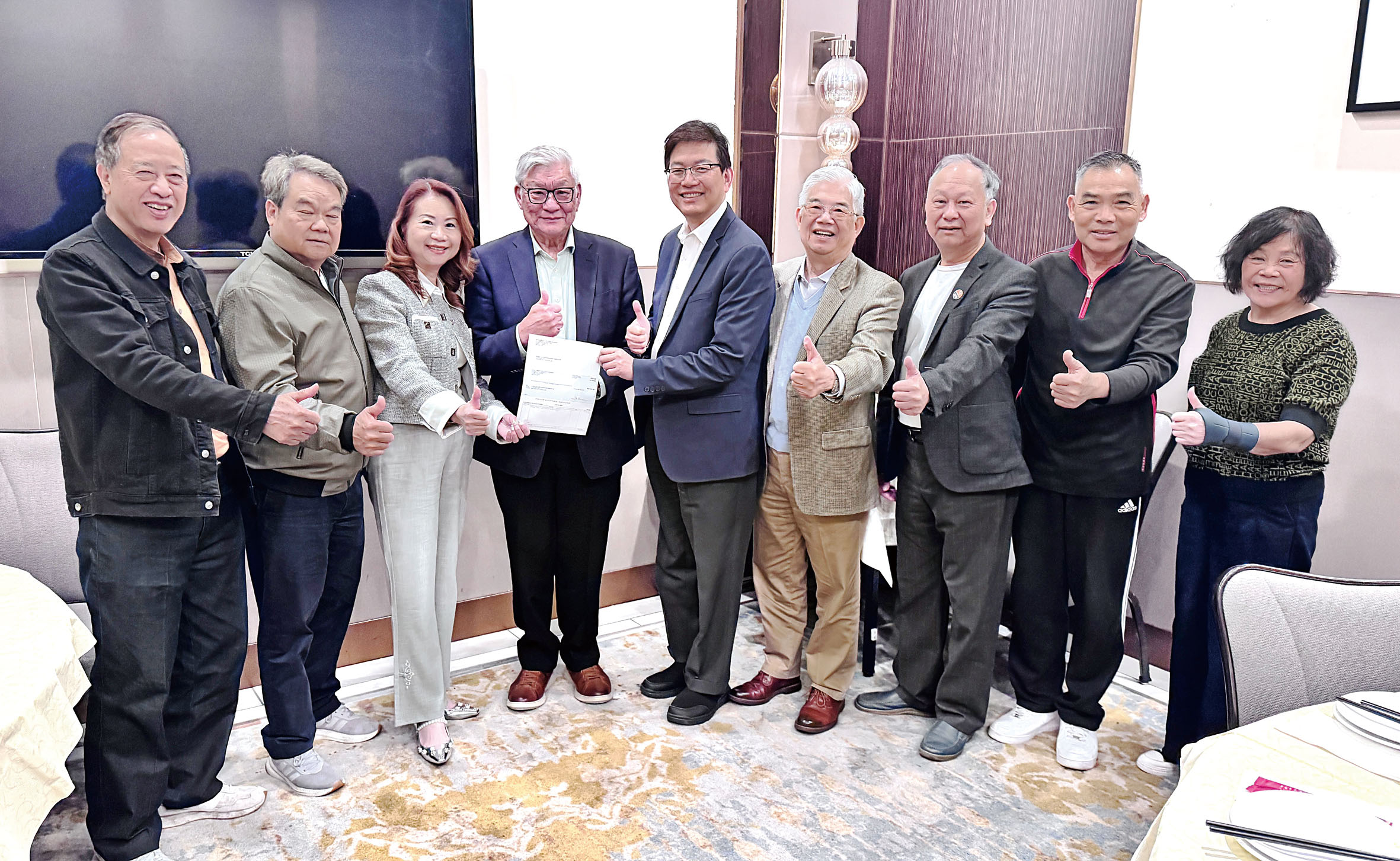 圖片左1董事陳啟光、左2副會長梁國強、左3財務長梁林靜宇、左4慈善家陳堅兒、中：會長梁建鋒、右4理事曾永燊、右3常務副會長曹樹堃、右2名譽會長陳萬祥、右1秘書長楊瑞明。