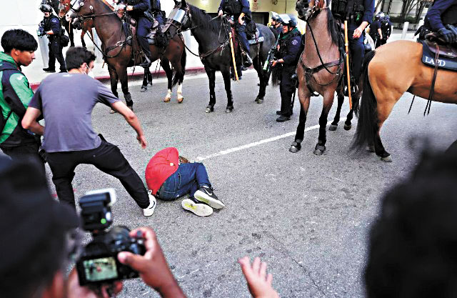 「反對國王」結束後，警員與抗議者對峙，一名男子倒地，群眾上前幫忙。洛杉磯時報