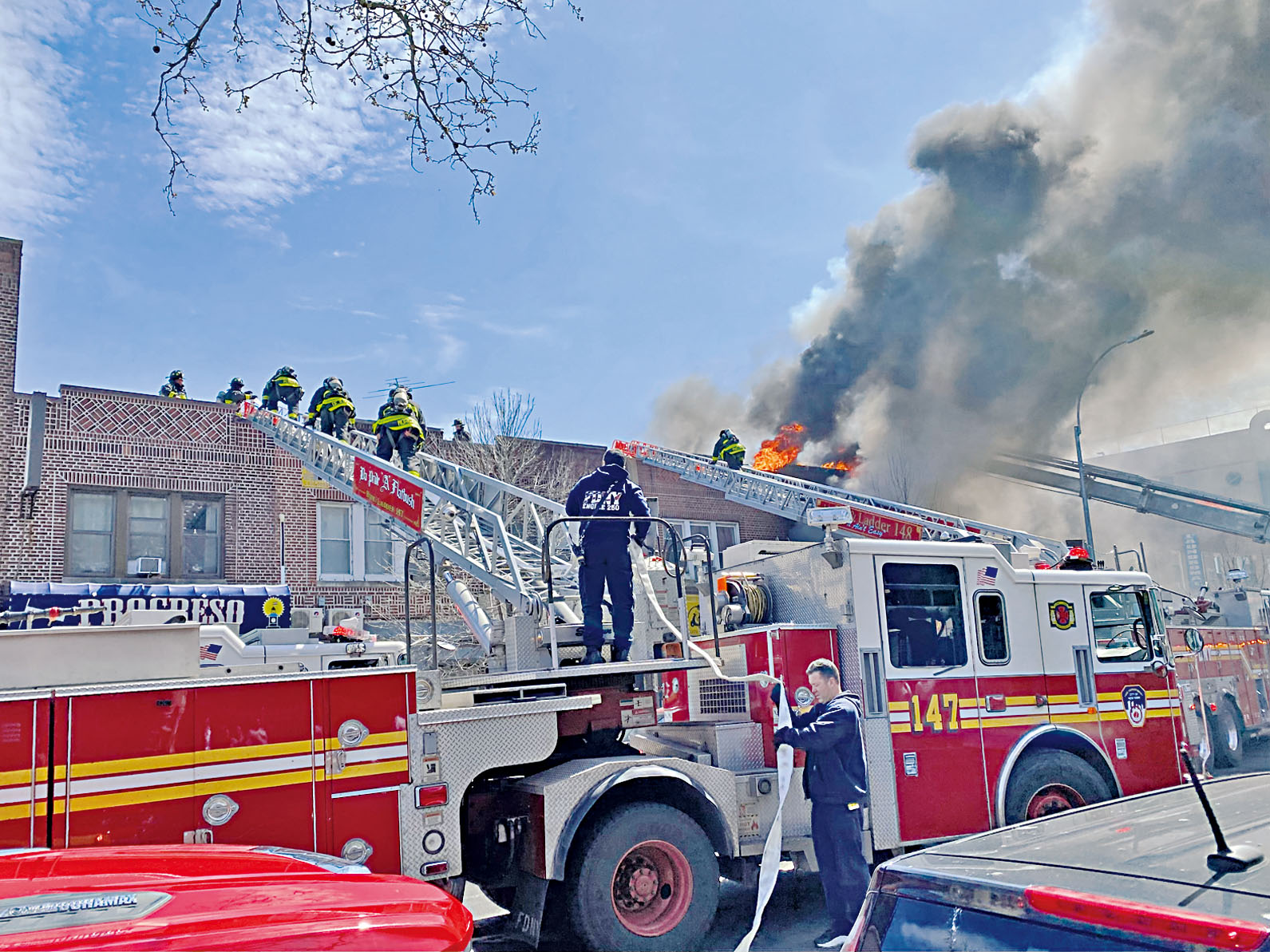 眾多消防員12日攀登雲梯救火。