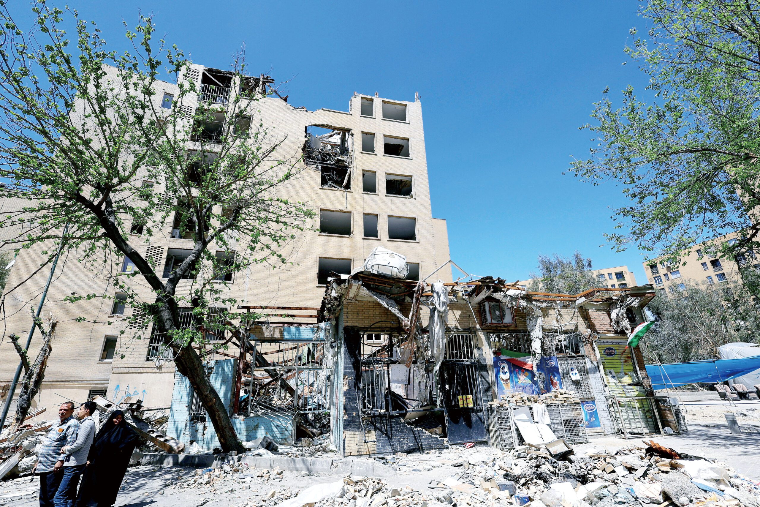 各界關注美伊談判進程，圖為在伊朗德黑蘭，民眾站在被炸毀的居民樓前。路透社