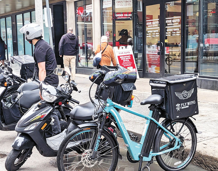 波士頓市中心一餐廳門口停放了多部外送員的電瓶車和電動自行車。