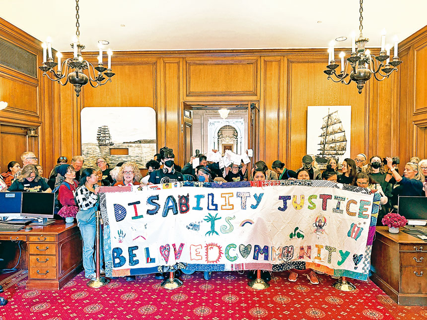 長者與殘障人士手持大型橫幅於市長辦公室外集會及遊行，抗議削減服務預算。記者蘇婕雅攝