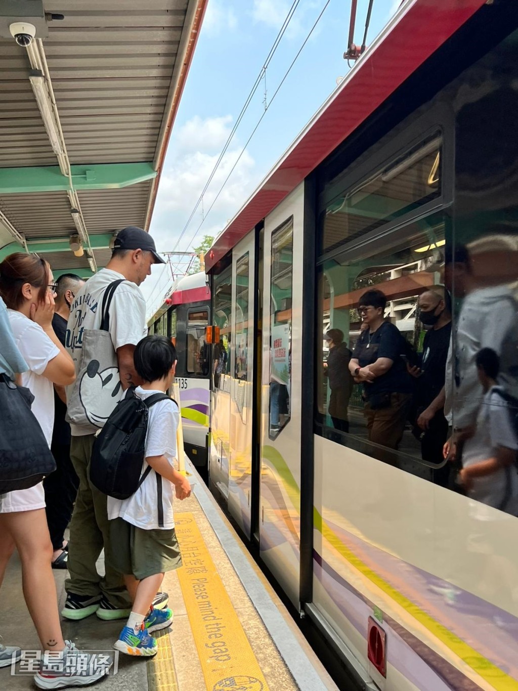 一家三口登上前往元朗方向的輕鐵列車。