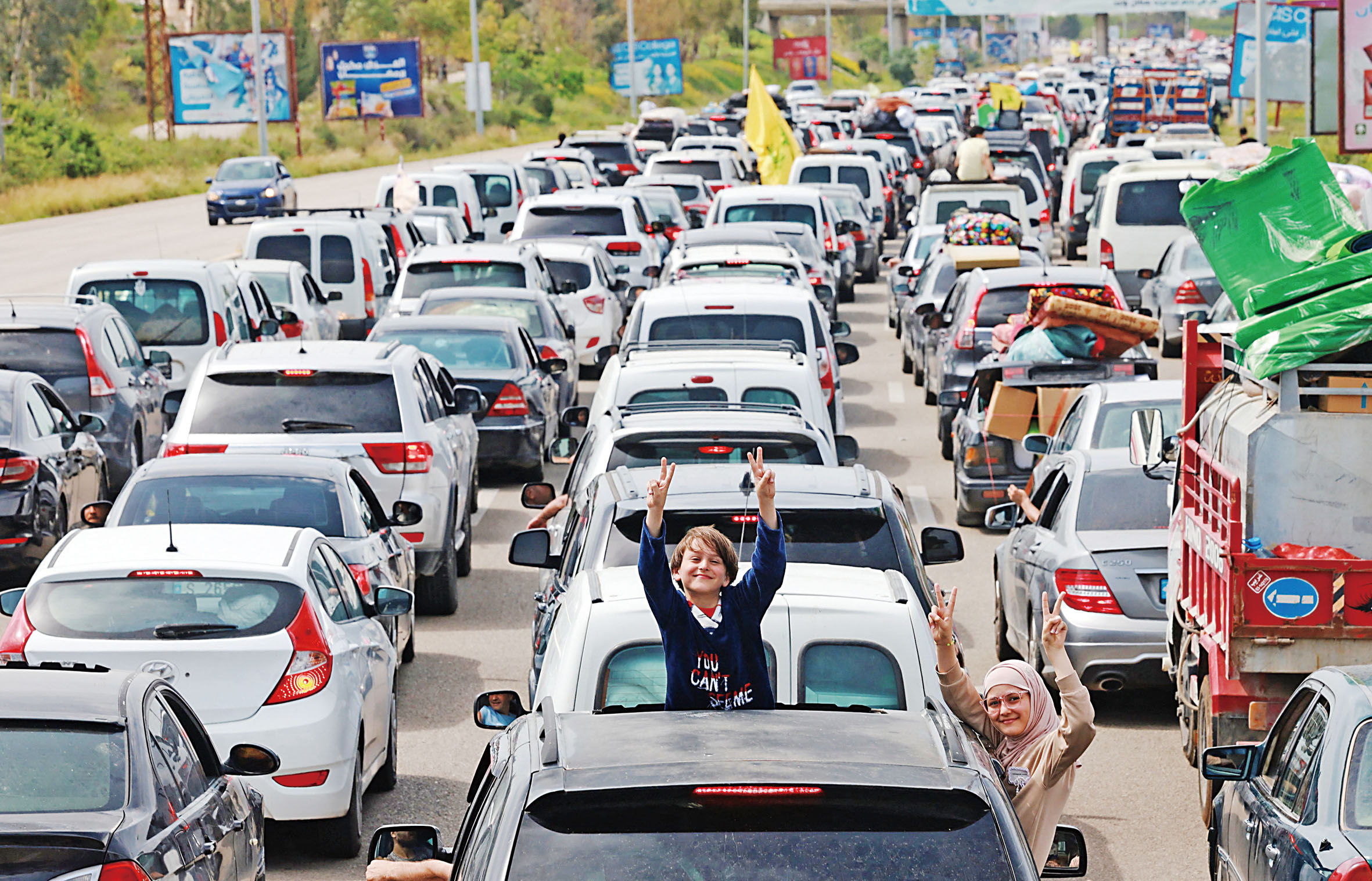 以黎為期10天的停火協議生效後，流離失所的人們返回家園，孩子從車裏開心揮手。路透社