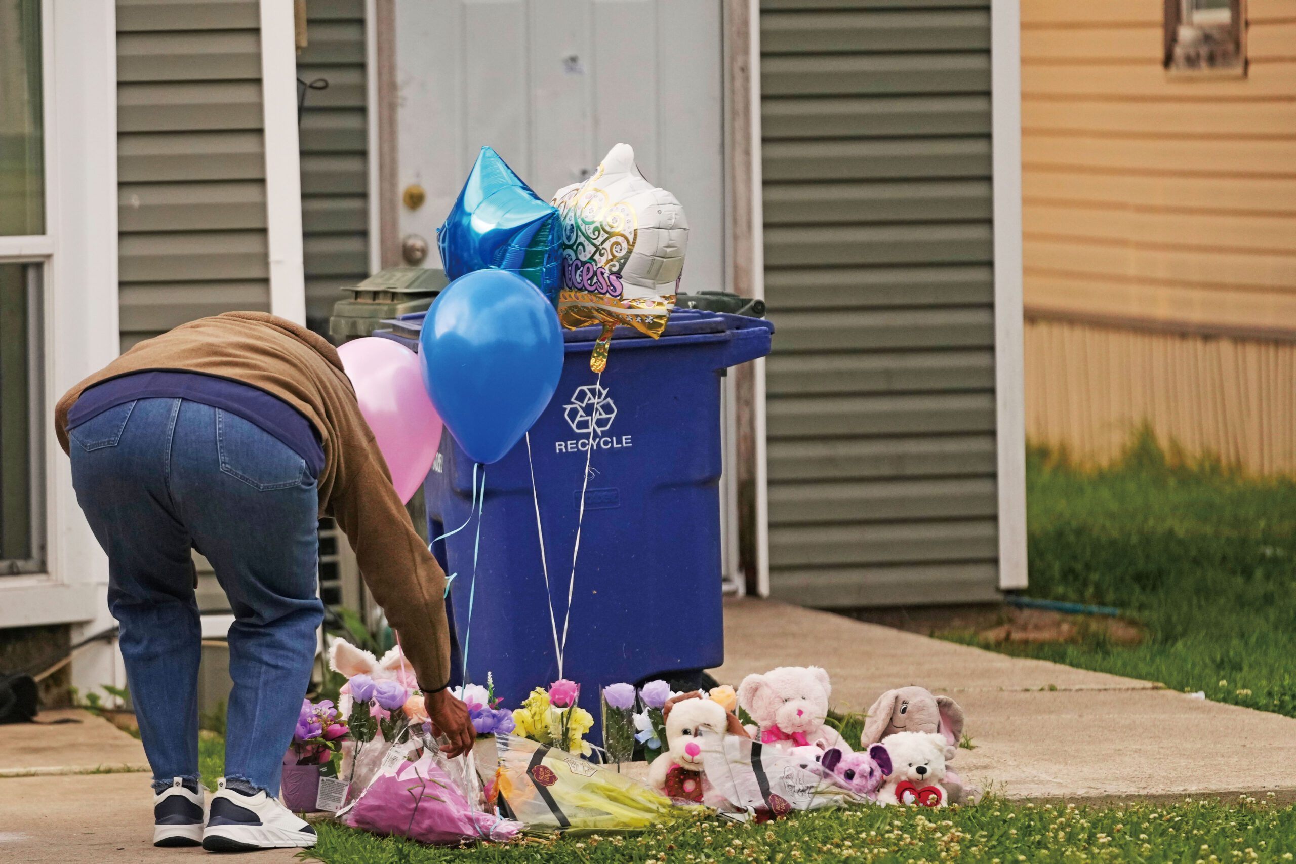 一名市民20日在大規模槍擊案草坪上臨時紀念處前留下禮物。 美聯社