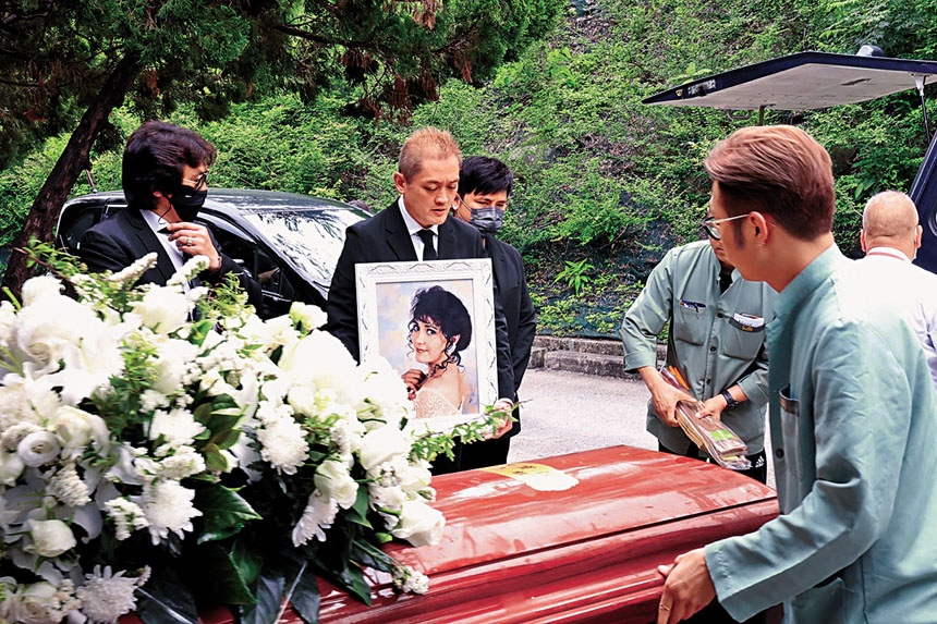 李泳漢捧亡母遺照，細佬豪仔在旁。