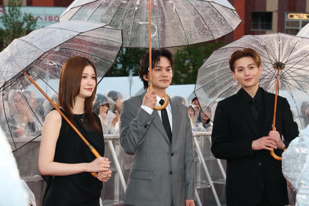 （左起）橫田真悠、北村匠海和八木勇征一同撐傘會見粉絲。