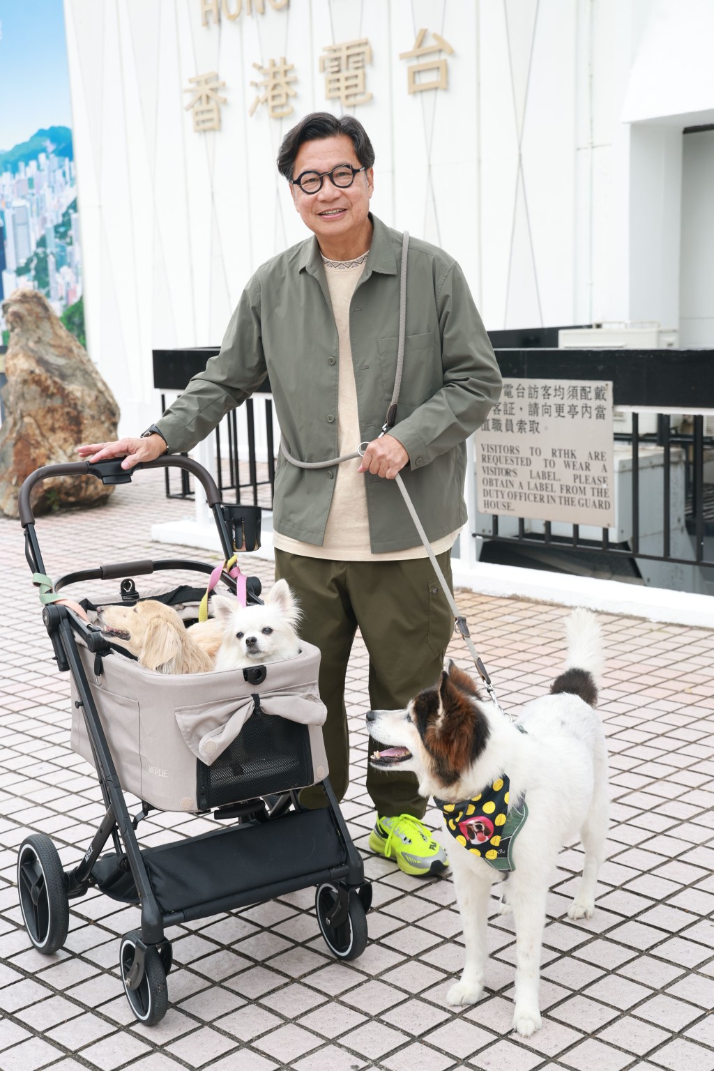 鄭子誠一手推着載有「多多」和「小初」的寵物車，一手牽着「歡歡」，樂在其中。