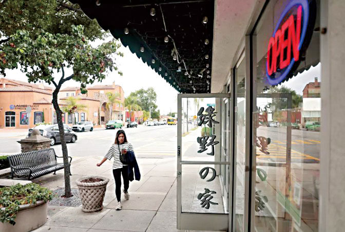 周二,一名行人經過亞凱迪亞市中心的一間餐廳。洛杉磯時報