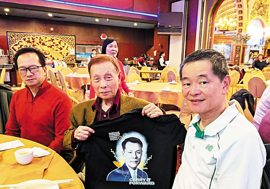 （左起）黃鷹立主席、手持印有譚金源照片T恤衫的黃官羡元老、黃納斯合影。李強攝