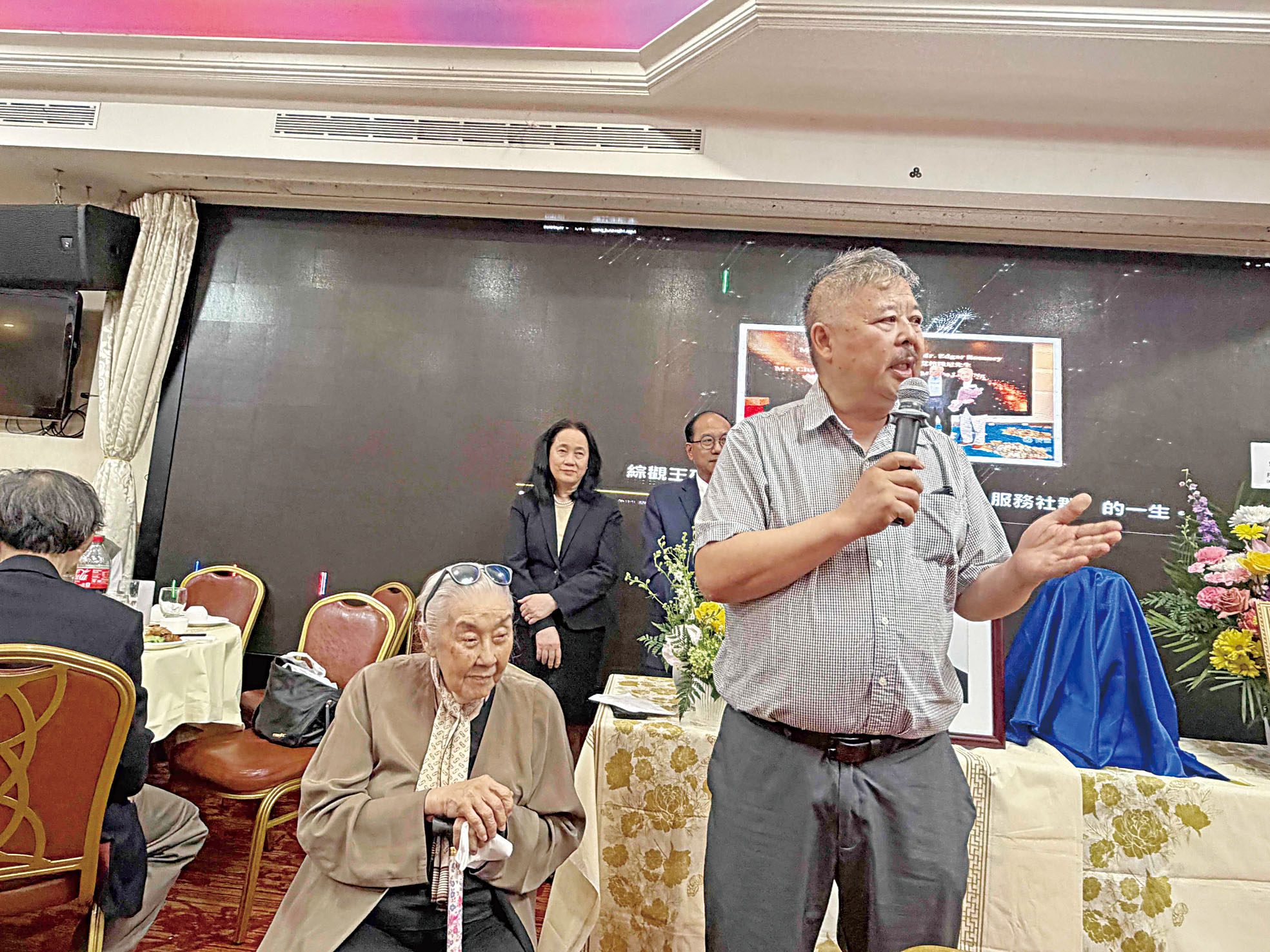 102歲的華人教師胡蘭貴在兒子孔振成扶持讚美王碚的服務精神。