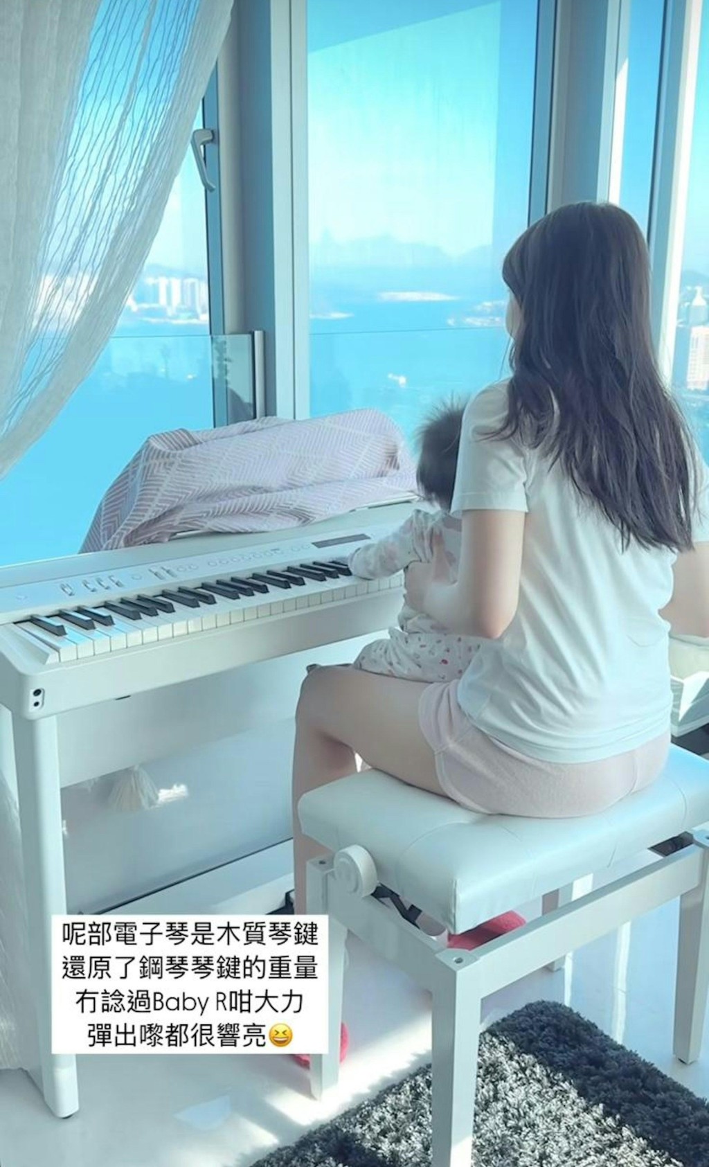 何依婷穿著家居服,抱著女兒坐在鋼琴前,女兒伸手觸碰琴鍵,母女互動溫馨。