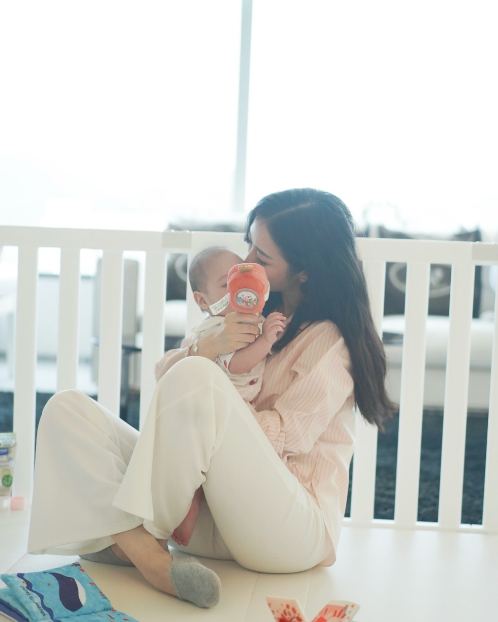 何依婷攬著女兒一邊玩玩具,一邊親吻女兒額頭,充滿愛意。