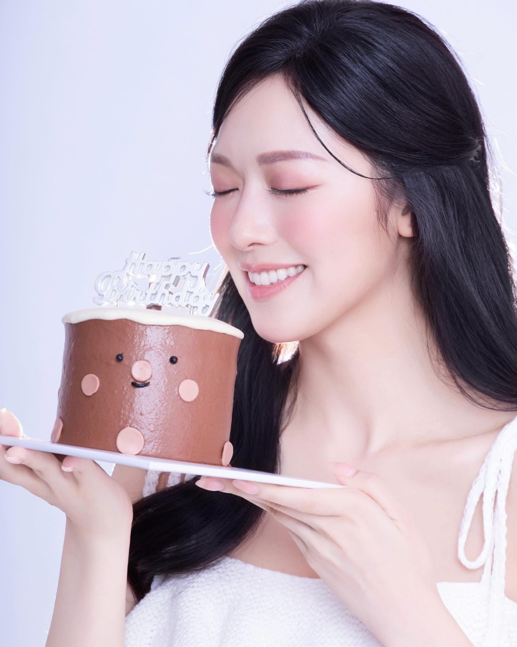 她手捧生日蛋糕,露出活潑笑容。