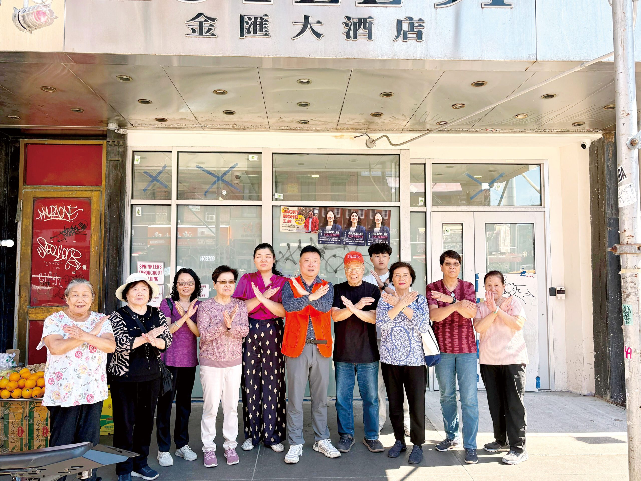 莊文怡 (左五)、王鏑(中)、于金山 (右五)與義工們一起在東百老匯91號作出反對到底的手勢。
