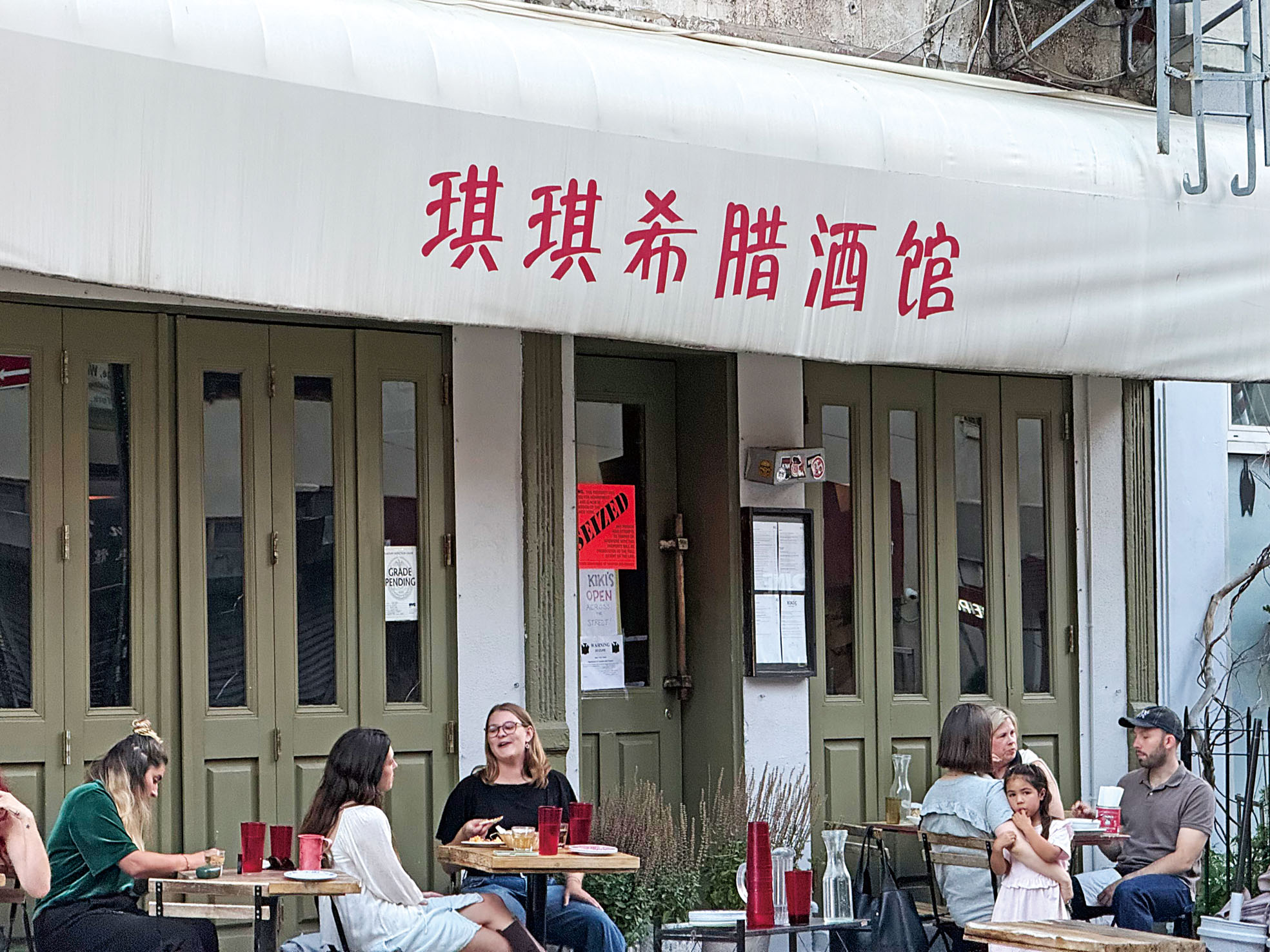 食客在被查封的地址外繼續享用該餐館從對面附屬經營空間製作的食物，身後查封通告醒目。