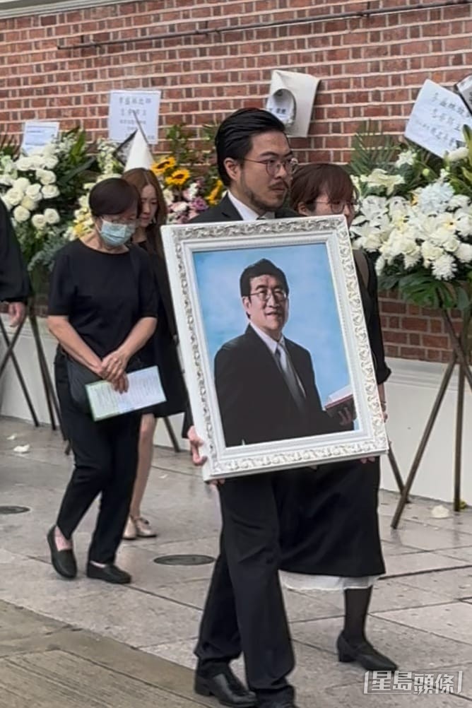 長子李啟旻醫生神情哀傷手捧父親遺照，弟弟阿Mo則因在醫院而未能親身送別。