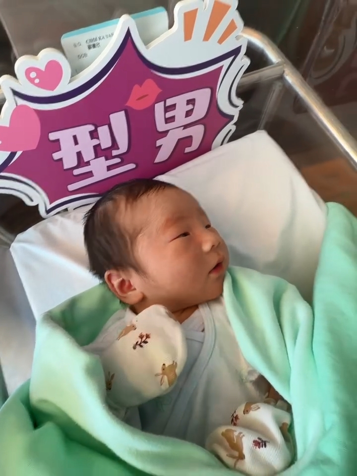 蔡嘉欣的兒子被溫暖的白色毛巾與淺綠色包被包裹著。